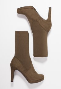 Botas de tacón alto en ante marrón con parte superior de punto elástico y puntera puntiaguda. Textura suave, diseño elegante y una plataforma moderada.