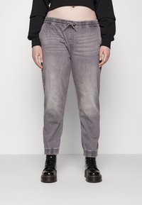 Pantalones jogger de mezclilla gris con cintura elástica, cordón ajustable y puños fruncidos. Textura suave con un acabado ligeramente desgastado.