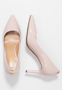 Escarpins à bout pointu en vernis rose pâle brillant avec une semelle intérieure beige. Présente un talon aiguille élancé et un design découpé.