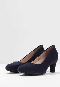 Escarpins en suede bleu marine avec une texture lisse, bout arrondi et un talon modéré. Dotés d'une semelle intérieure rembourrée pour plus de confort.