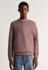 Pullover in un delicato color malva, in tessuto testurizzato, con scollo rotondo bianco, polsini a costine e un sottile accento del logo sul petto.