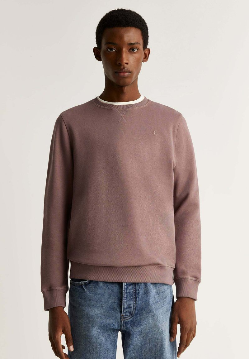 Pullover in un delicato color malva, in tessuto testurizzato, con scollo rotondo bianco, polsini a costine e un sottile accento del logo sul petto.