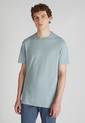 T-shirt bleu clair à manches courtes en tissu doux, avec un col rond et une coupe décontractée. Texture lisse sans motifs visibles.