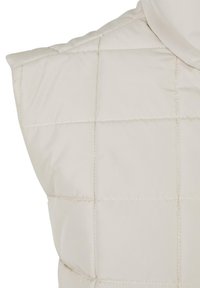 Padded prsluk u svijetlo bež boji, sa kvadratnim quilted uzorkom i visokim ovratnikom, glatke teksture i suptilnim detaljima šivanja.
