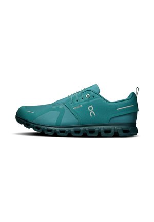 Chaussure de sport imperméable couleur sarcelle avec semelle coussinée, design à lacets et bande réfléchissante au talon, vue de côté sur fond blanc.