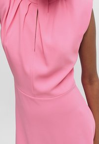 Rosa ärmelloses Kleid aus glattem Stoff, mit einem plissierten Ausschnitt und einem Schlüssel-Loch, taillierter Silhouette und minimalen Nähten.