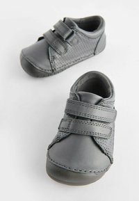 Chaussures en cuir gris avec design perforé, dotées de deux sangles réglables en Velcro et d'un bout rond. Semelle texturée pour une meilleure adhérence.