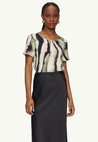 Bluse mit floralem Druck in Grün, Pink und Marineblau, mit kurzen Ärmeln und plissiertem Design, kombiniert mit einem einfarbigen schwarzen knöchellangen Rock.