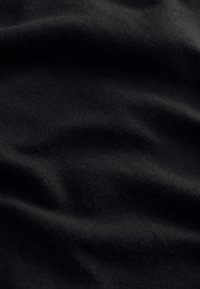 Tessuto nero con pieghe morbide e una texture liscia, che mostra riflessi di luce sottili e dettagli di trama fine.