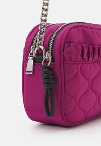 Borsa a tracolla in nylon rosa trapuntato con cerniere argentate, dotata di una tracolla a catena e di un manico annodato nero. Accenti testurizzati lungo i lati.