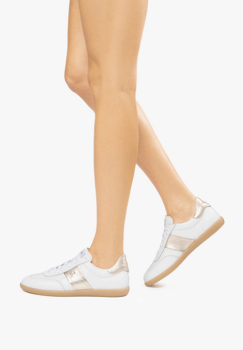 Witte leren sneakers met een metallic gouden accent, vetersluiting en een tan rubberen zool. Soepele textuur met glanzende elementen.