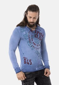 Langärmliges blaues Hemd mit gedruckten Grafiken in Rot und Grün, mit Rundhalsausschnitt und taillierter Passform, aus einem weichen Baumwollmix gefertigt.