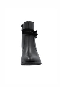 Bottine noire avec un extérieur en cuir lisse, fermeture éclair latérale et un détail de nœud décoratif. Elle possède une semelle basse et plate pour plus de stabilité.