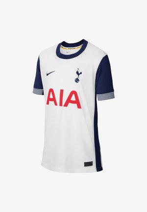 Camiseta de fútbol blanca con detalles en azul marino, cuello redondo, mangas cortas, que presenta un gran logo rojo "AIA" y un emblema del club en el pecho.