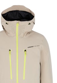 Beige wasserfeste Jacke mit schwarzem Innenfutter, ausgestattet mit neon gelben Reißverschlüssen, einer durchlüfteten Kapuze und zwei vorderen Reißverschlusstaschen.