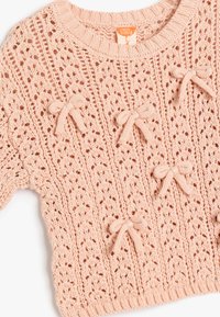 Jasnoróżowy sweter z dzianiny z koronkowym wzorem i małymi kokardkami jako akcentami. Żebrowany dekolt i mankiety dodają tekstury.