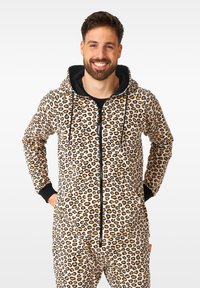 Leopard print onesie featuring a beige background with black and orange spots, a zip front, black trim, and a hood. Soft fabric texture.