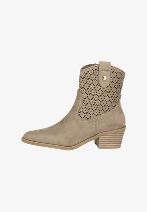 Botín beige de ante con diseño recortado, puntera afilada y tacón apilado. Presenta una pestaña y herrajes decorativos en color dorado.