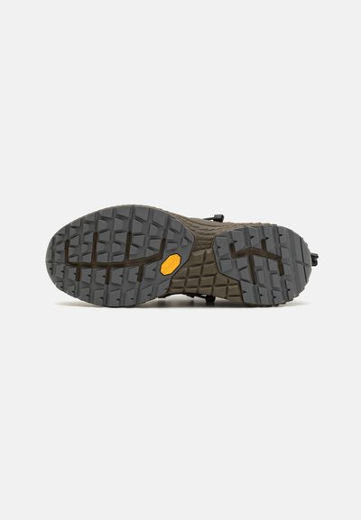 Semelle de chaussure avec un design en caoutchouc gris robuste, dotée d'un motif de grip texturé et d'un logo Vibram jaune, idéale pour la traction sur divers terrains.