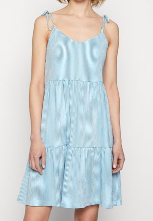 Ærmeløs blå og hvid vertikalstribet kjole med tynde bindestropper og et løst, lagdelt skørt, der falder over knæene.
