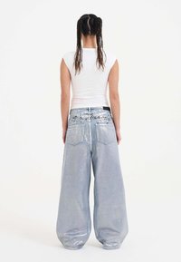Light blue wide-leg denim jeans with a glossy texture, featuring oversized cut, two back pockets, and intricate dark stitching details.