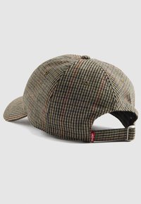 Casquette de baseball à carreaux dans des tons de marron et de vert, avec une visière courbée, une sangle ajustable et une petite étiquette logo rouge à l'arrière.