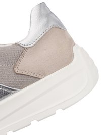 Gros plan sur le talon d'une basket en daim beige, tissu gris, accents en cuir argenté et semelle épaisse en caoutchouc blanc avec semelle à motifs texturés.