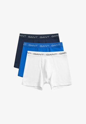 Tre boxer da uomo impilati in bianco, blu e blu navy, ciascuno con una fascia in vita con il marchio "GANT" in testo a contrasto.