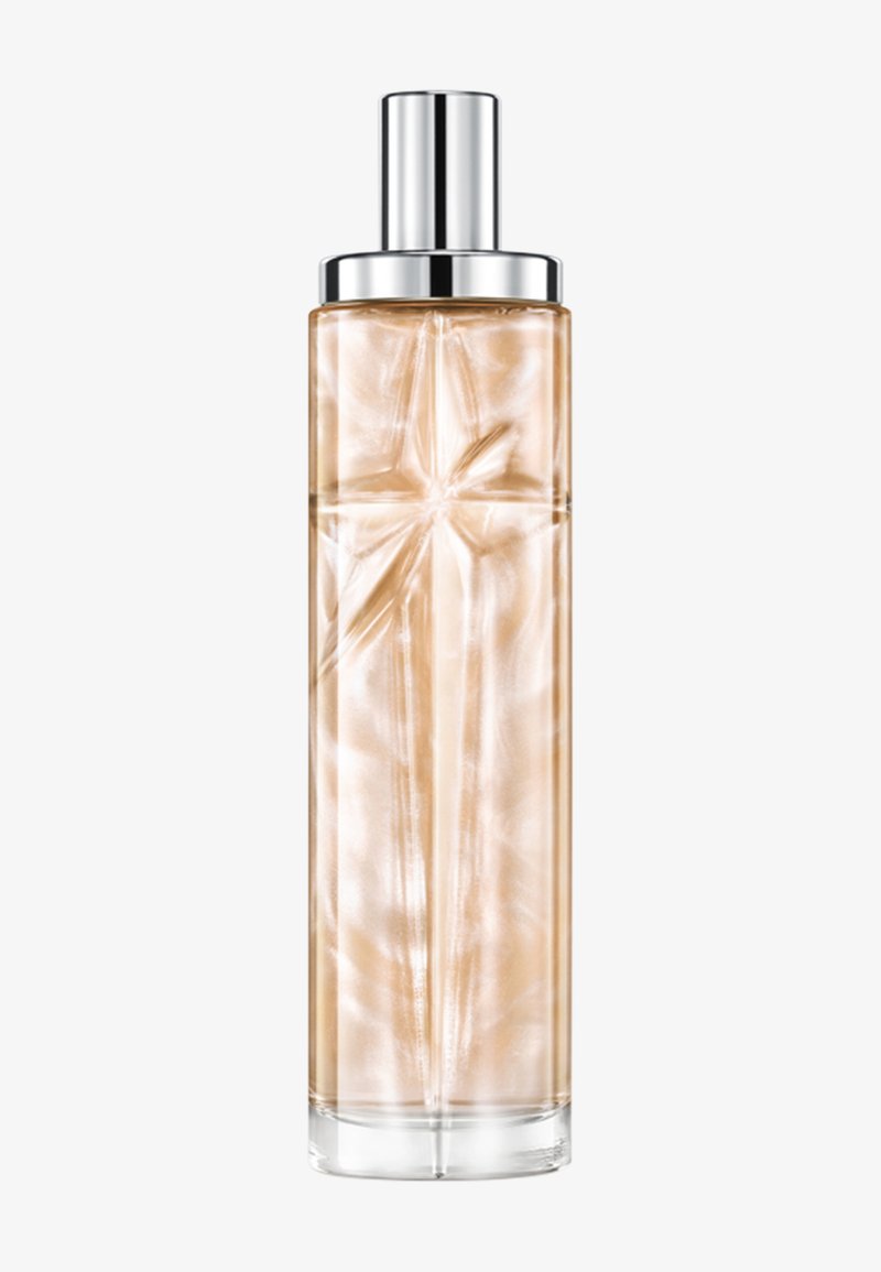 Botella alta y transparente de perfume con un líquido beige nacarado y una tapa plateada sobre un fondo claro y sencillo.