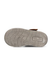 Bruine suède schoen met een gestructureerde bruine band, voorzien van een witte rubberen zool met een patroon op de onderkant en een reliëflogo op de zijkant.