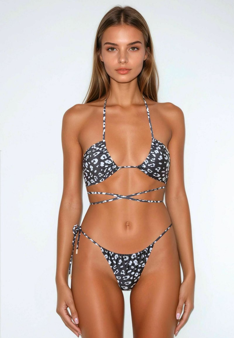 Bikini leopard print bianco e nero con top triangolare dotato di spalline regolabili e fondo con laccio laterale, caratterizzato da una texture liscia.