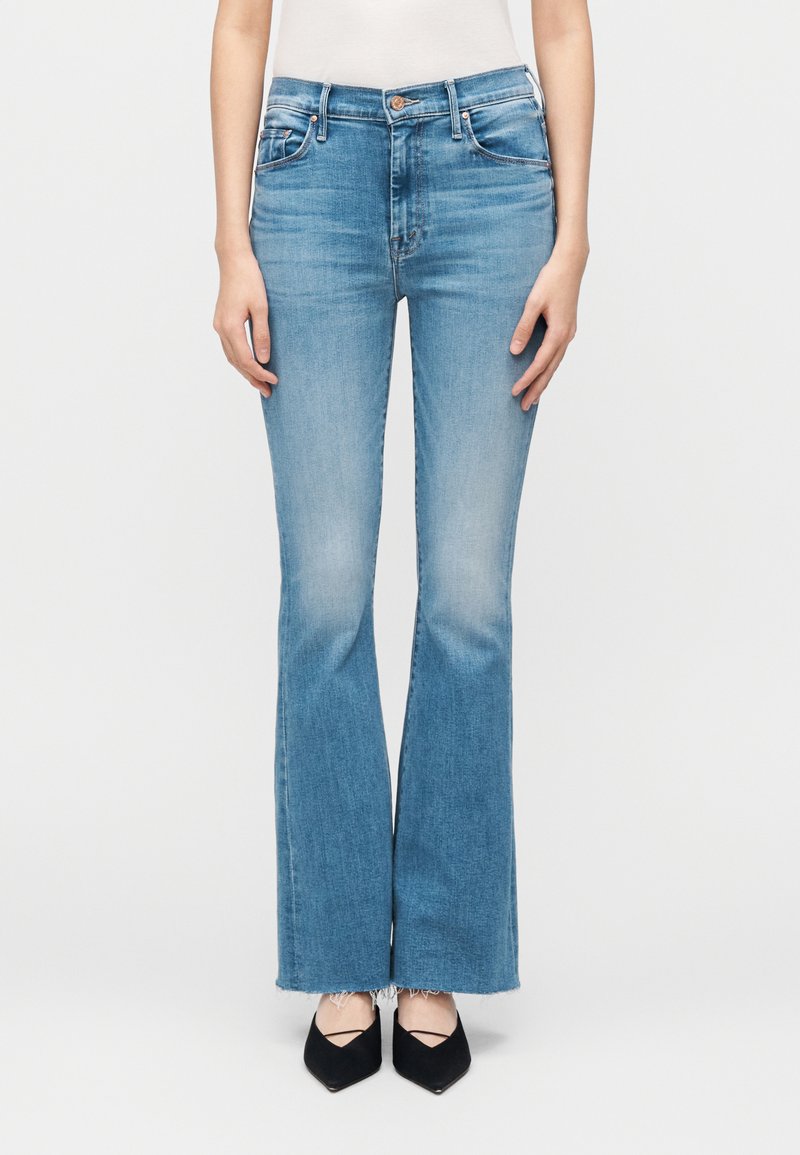 Széles szárú világoskék farmer öt zsebes kialakítással és bolyhos szegéllyel. Deréknál karcsúsított szabás, fekete magassarkúval párosítva.