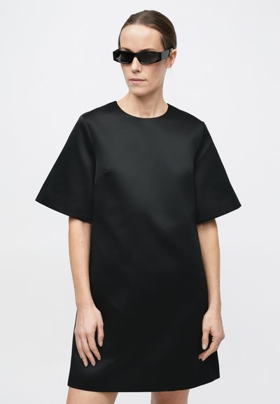 Sort kortærmet kjole lavet af et glat, mat stof med rund halsudskæring. Har en løs, oversized pasform og en ren silhuet.