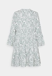 Robe blanche à étages avec manches larges et motif abstrait ondulé gris-vert, vue de dos sur un fond uni.