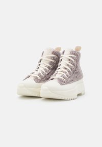 Höga sneakers med fluffig lila och krämfärgad tygöverdela, vit gummisula, tjock plattform och kontrasterande texturerade detaljer.