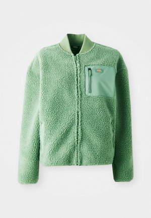 Green fleece jacket with a textured surface, featuring a zippered chest pocket and a ribbed collar. Front zip closure, long sleeves.