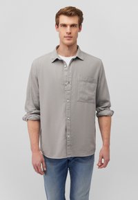 Gray button-up shirt made of soft fabric with a textured finish, featuring a chest pocket and rolled sleeves, paired with blue jeans.