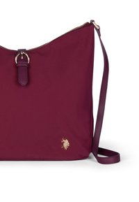 Borsa in nylon bordeaux con hardware dorato, chiusura con zip, tracolla regolabile e logo in evidenza sul davanti. Forma arrotondata con una texture liscia.