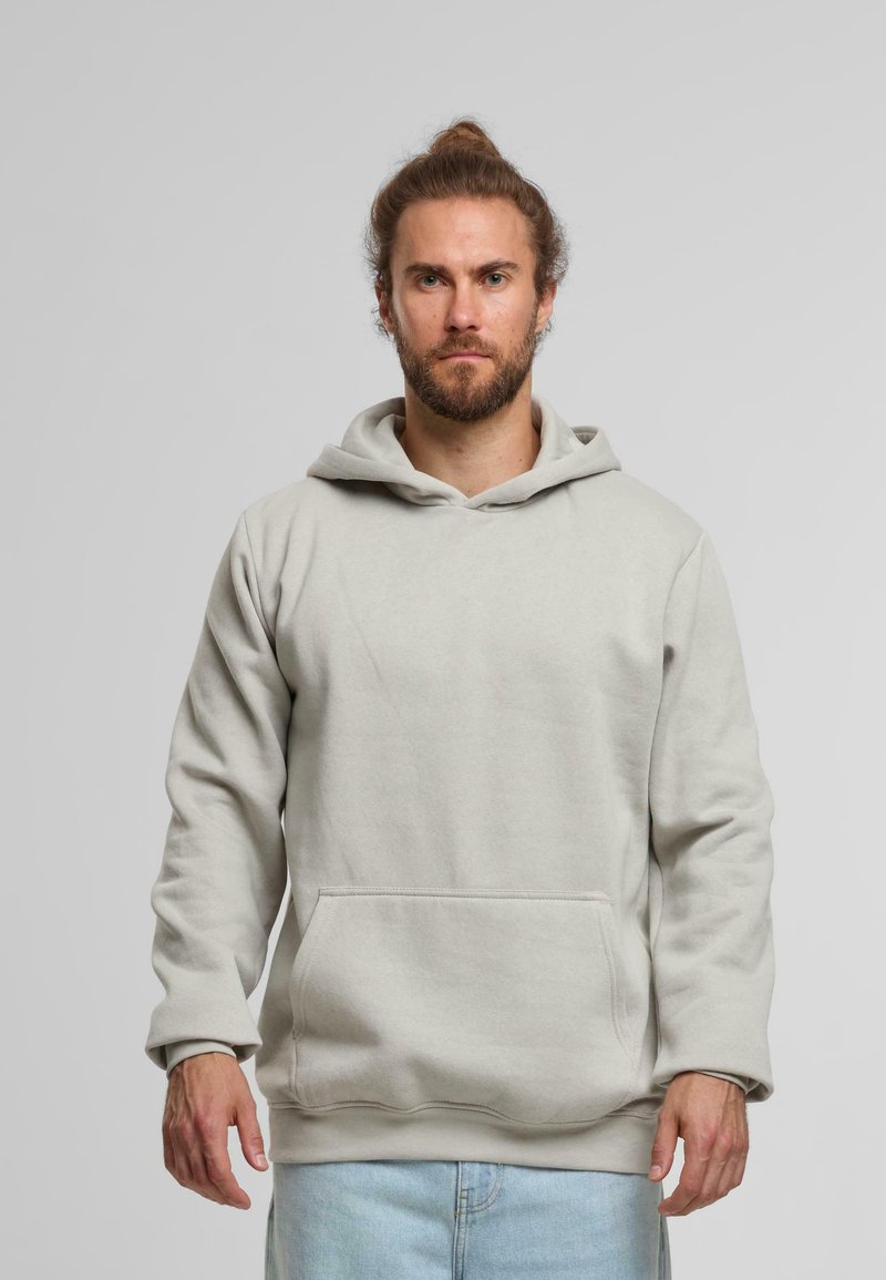 Světlě šedá mikina s kapucí vyrobená z měkké tkaniny, která disponuje klokankovou kapsou a žebrovanými manžetami. Jednoduchý, uvolněný design bez vzorů.
