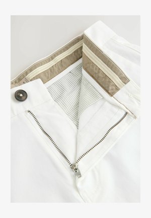 Fehér nadrág cipzárral és gombos záródással. Belső részén csíkos és mintás bélés található bézs és szürke díszítéssel.