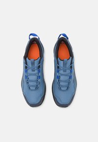 Blue athletic shoes with a textured upper, reinforced toe, and black rubber sole. Features orange insole and blue laces for secure fit.