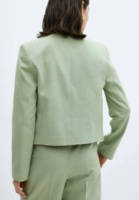 GREEN BLAZER: Tailored cut, lightweight fabric, cropped length, long sleeves, minimalistic design, smooth texture, rear view displayed.