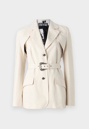 Beige tailored blazer with two front pockets, single button closure, belt with ornate metallic buckle, and notch lapel design.