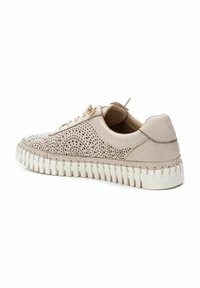 Zapatillas de piel beige con un patrón decorativo de perforaciones, puntera redonda y suela de goma blanca con estrías texturizadas. Cordones y bucle en el talón.