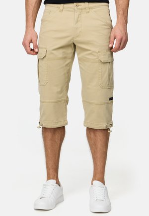 Shorts cargo khaki avec de multiples poches, design longueur genou, ourlets ajustables, fabriqués à partir de tissu durable, associés à des baskets blanches.