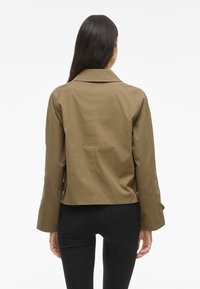 Olive green, mid-length jacket with a classic collar, long sleeves, and a relaxed fit; features button accents on the sleeves.