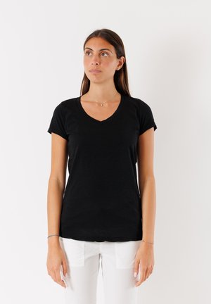 T-shirt nera con scollo a V realizzata in tessuto morbido, con maniche corte e design aderente, abbinata a pantaloni bianchi. Stile minimalista senza motivi.