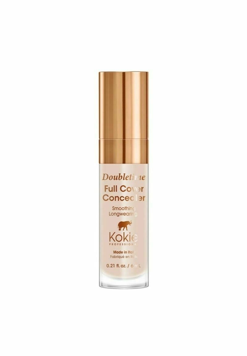 Kokie Doubletime Full Cover Concealer i en klar glas pumpeflaske med en skinnende guldkappe; produktnavn og oplysninger er trykt i guld.