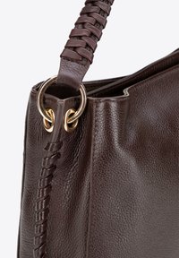Bruine lederen handtas met een gestructureerde afwerking, voorzien van een gevlochten schouderband en gouden hardware. Aangevuld met ronde ringen aan de bevestiging.