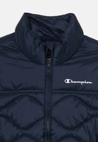 Námornícky puffer kabát s vysokým golierom, prešívaným vzorom, zipsovým zapínaním a bielym logom Champion na ľavom prsníku. Hladká, lesklá tkanina.